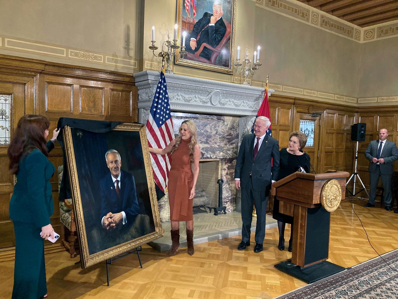 Hutchinson and his wife, Susan, watch as their granddaughter, Jaella Wengel, left, and daughter, Sarah Wengel, unveil his official portrait at the State Capitol in January 2023.