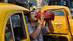 A taxi driver is seen drinking water from a bottle during afternoon heat in Kolkata, India, on April 18, 2023.
