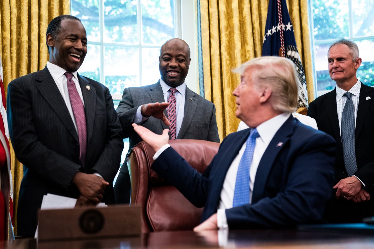 Trump reaches out to Scott in June 2019 as he signs an executive order establishing a White House Council on eliminating regulatory barriers to affordable housing. At left is former Housing and Urban Development Secretary Ben Carson.