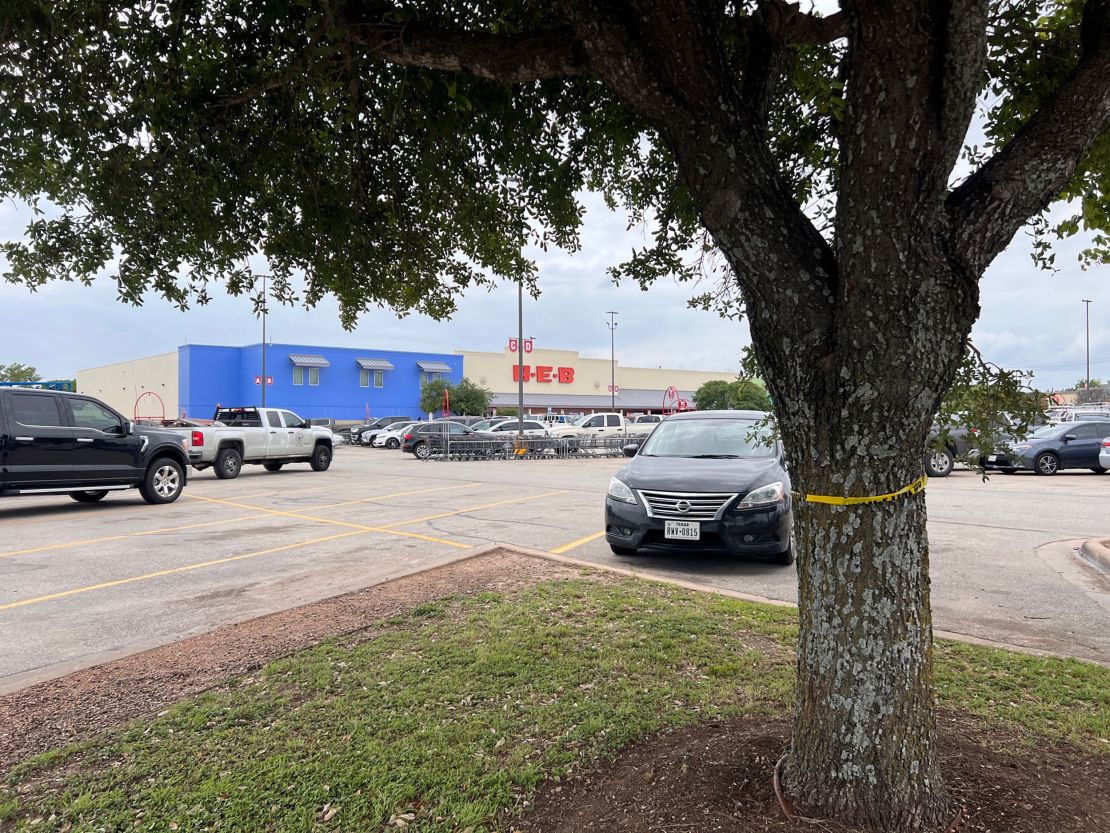 Crime scene tape winds around a tree Wednesday at the H-E-B parking lot  where a shooting erupted,  injuring two teens in Elgin, Texas.