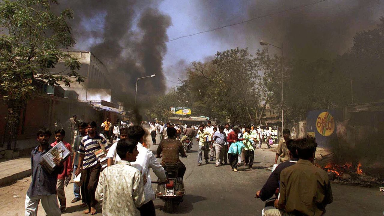 Smokes fill the air as looters walk through the streets in Ahmadabad, India, on February 28, 2002. 