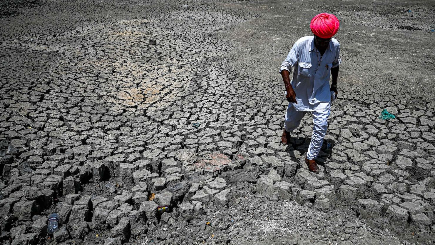 A villager walks through a dried-out pond on a hot summer day at Bandai village in Pali district on May 11, 2022. 