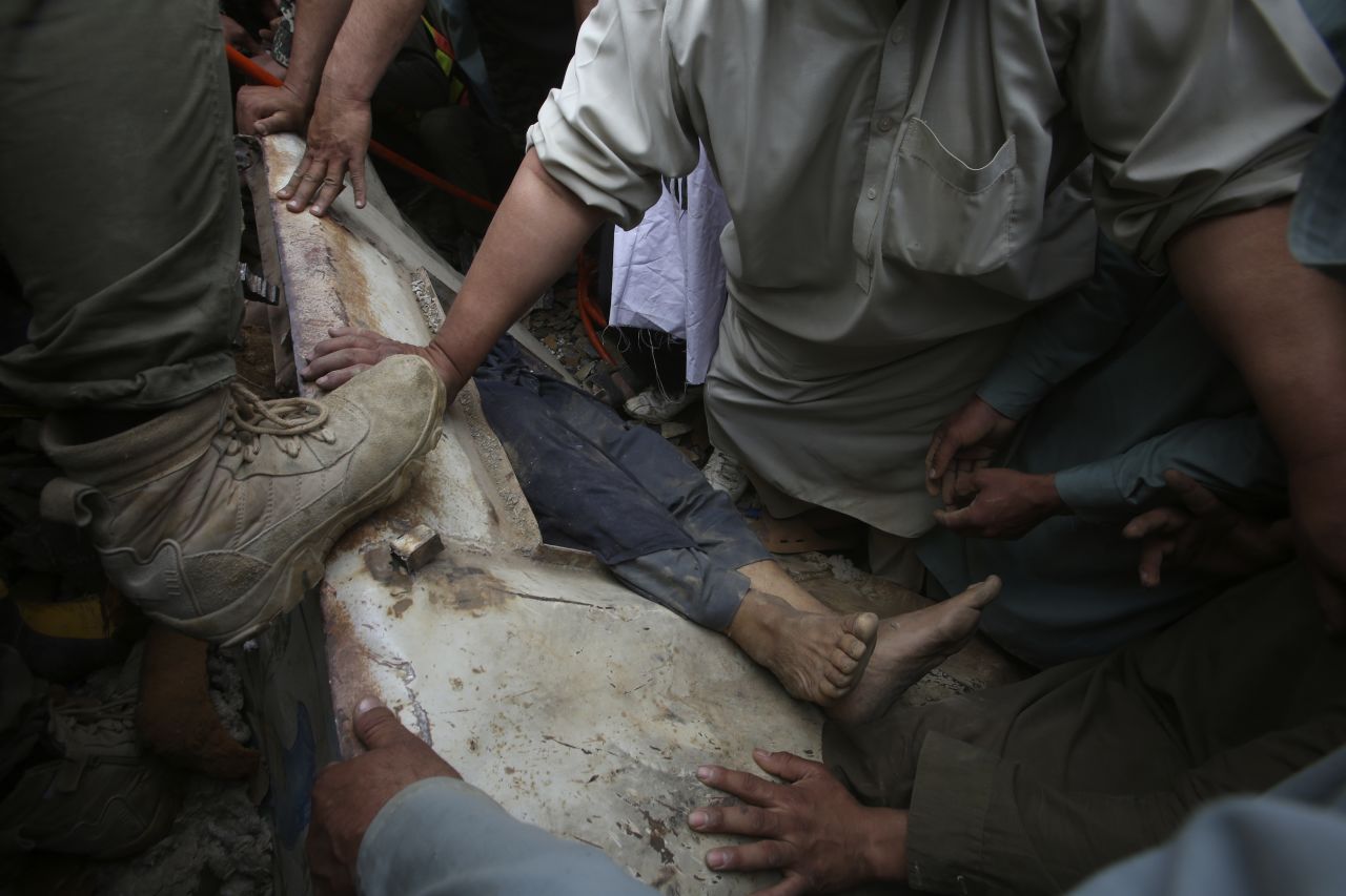 Rescue workers and volunteers recover a body from the rubble Tuesday, April 18, after a landslide near Torkham, Pakistan.