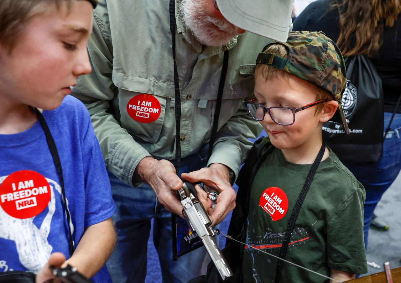 Daniel Eckart shows different handguns to his grandsons while attending the National Rifle Association's annual convention Saturday, April 15, in Indianapolis.