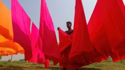 A worker collects dyed fabric after drying it under the sun at a dyeing factory.