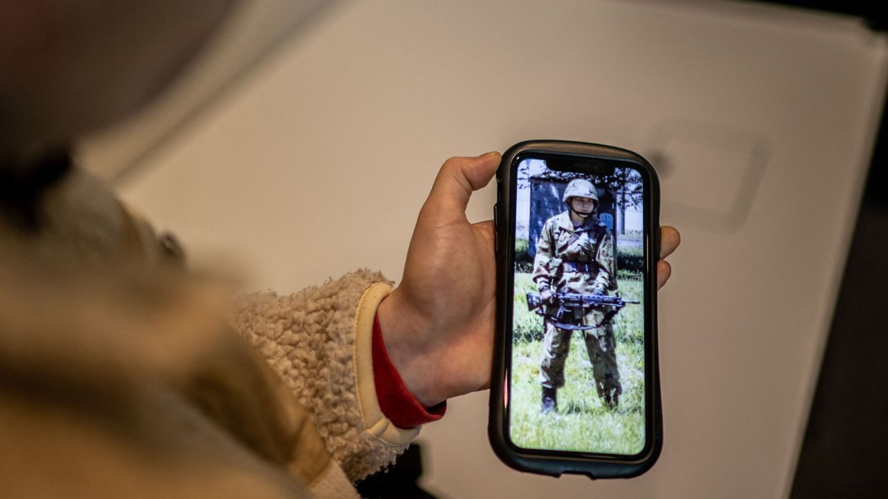 Rina Gonoi, a former member of Japan's Ground Self-Defense Force, checks old photos on her phone.