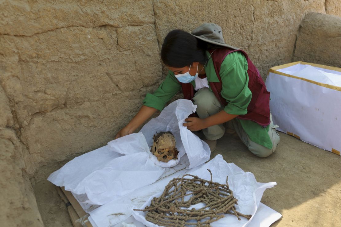 A worker wraps skeletal remains and parts of the mummy's funerary bundle.