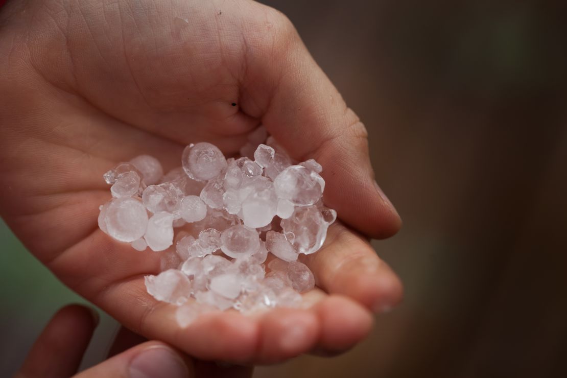 A boy holds hailstones after a storm.