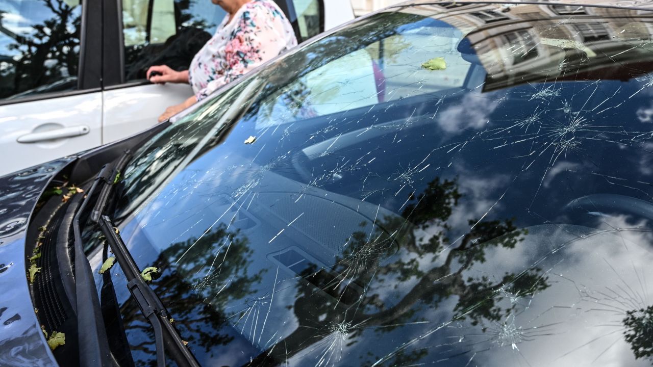 A woman walks past a car hit by a hailstorm in southeastern France.