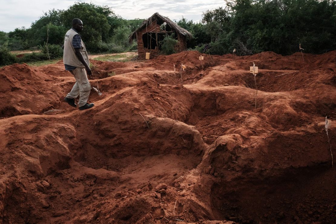 An officer of the Directorate of Criminal Investigations walks at the mass-grave site in Shakahola. 