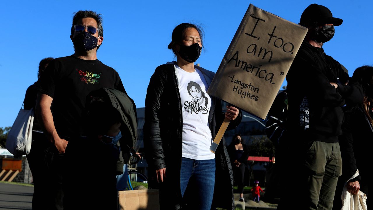 Jessica Jung of Oakland holds a sign bearing the famous Langston Hughes quote, "I, too, am America," as hundreds gather in memory of the Atlanta spa shooting victims.
