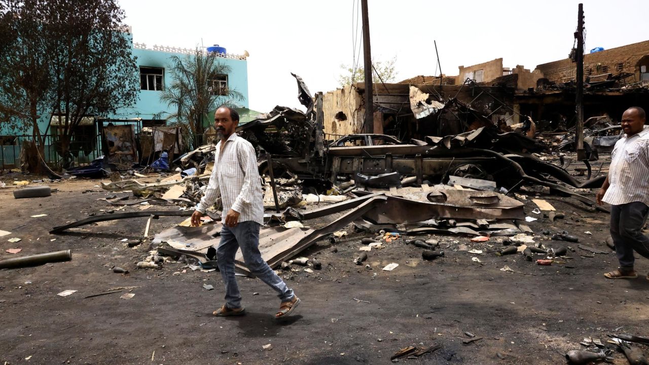 Men walk past shells on the ground near damaged buildings in Khartoum North in Sudan on Thursday, where the violence has left some locals trapped inside their homes.