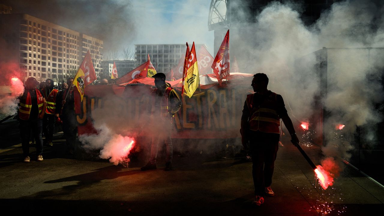 A protester lights a flare as railway workers demonstrate a few days after the government pushed its pension reforms through parliament without a vote.