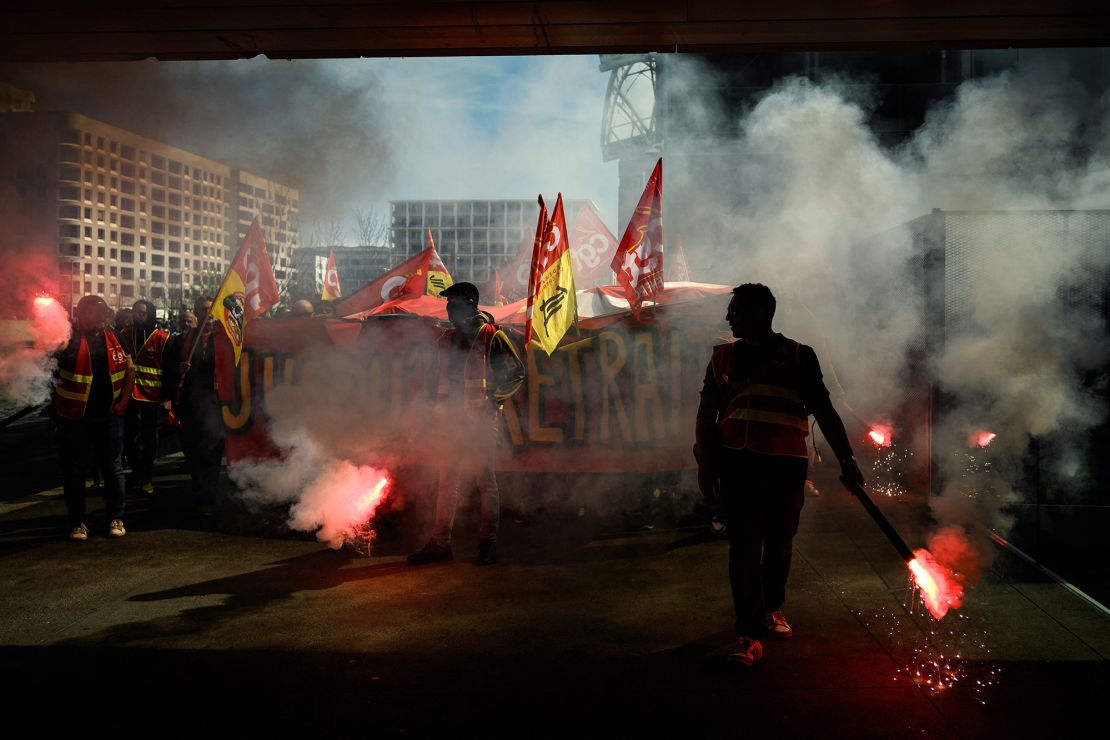 A protester lights a flare as railway workers demonstrate a few days after the government pushed its pension reforms through parliament without a vote.