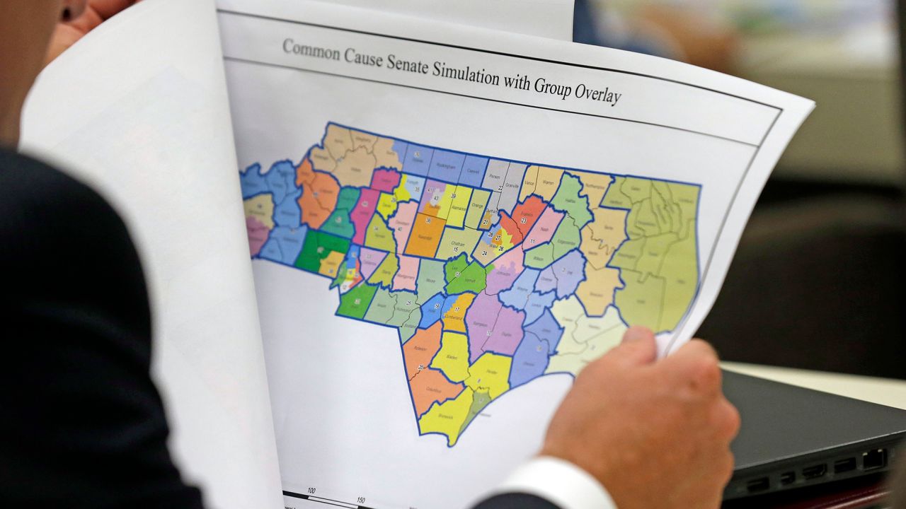In this July 26, 2017, file photo, a lawmaker studies a district map during a joint select committee meeting on redistricting in Raleigh, North Carolina.
