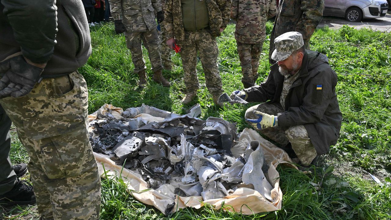 Ukrainian servicemen examine debris in a cordonned-off perimeter in Uman.