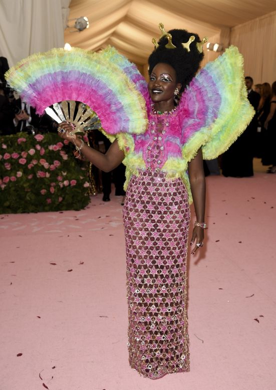 Lupita Nyong'o celebrates the 2019 Costume Institute's exhibition "Camp: Notes on Fashion,'' in a rainbow, frilly Versace number, bedecked with pink stars.