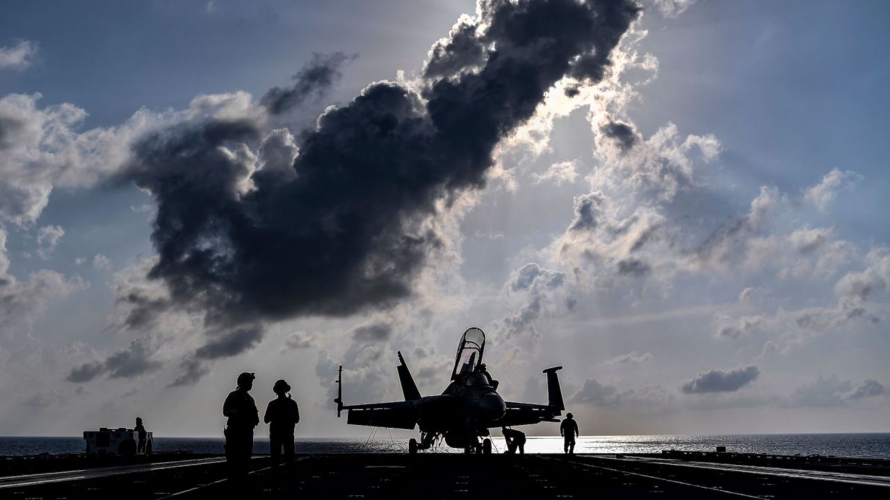 Crew members of US aircraft carrier USS Harry S Truman stand beside an F18 Hornet fighter jet on the flight deck of the ship in the eastern Mediterranean Sea on May 8, 2018.
