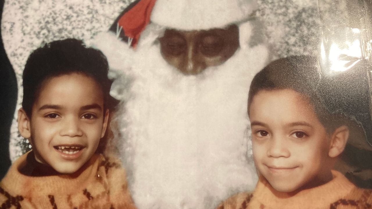 John Blake, left, with his younger brother, Patrick, sitting with Santa. Both boys grew up not knowing why their White mother disappeared from their lifes and why they had no contact with their White relatives.