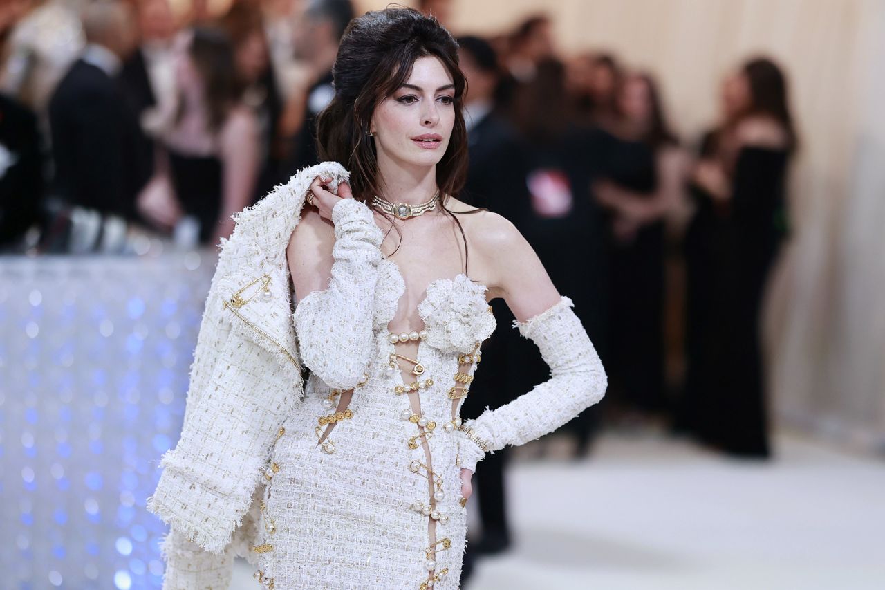Anne Hathaway's embellished Versace tweed dress included  safety pin details, a long train, matching jacket and arm bands.