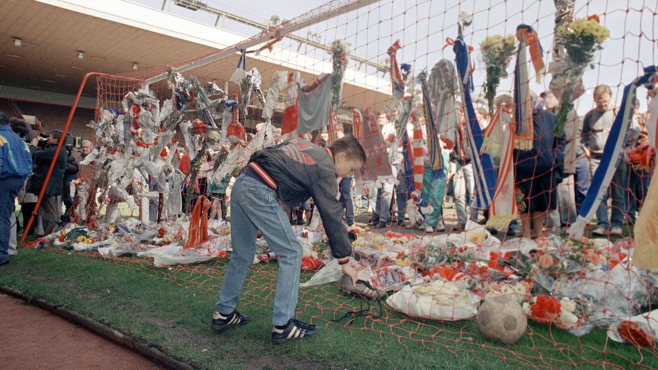 A young Liverpool fan places a pair of football boots in the goal at the Kop end of Anfield Stadium on April 16, 1989.