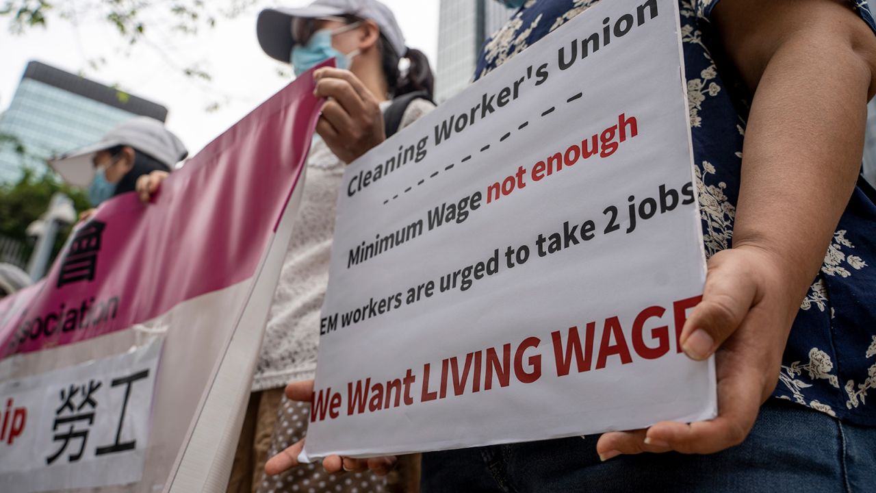 A women holds up a placard asking for a living wage in front of the Central Government Office in Hong Kong on May 1, 2023.