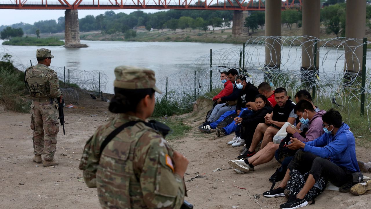 Migrants who had crossed the Rio Grande River into the US are under custody of National Guard members as they await the arrival of US Border Patrol agents in Eagle Pass, Texas, on May 20, 2022.