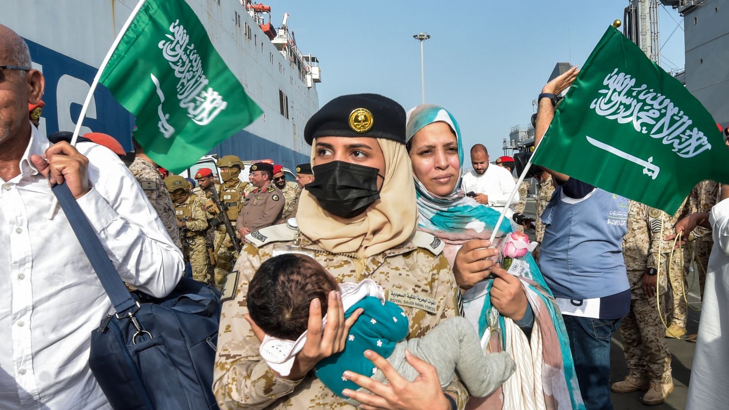 A Saudi Navy sailor carries a child as evacuees arrive at King Faisal Navy Base in Jeddah on April 26 following a rescue operation from Sudan.