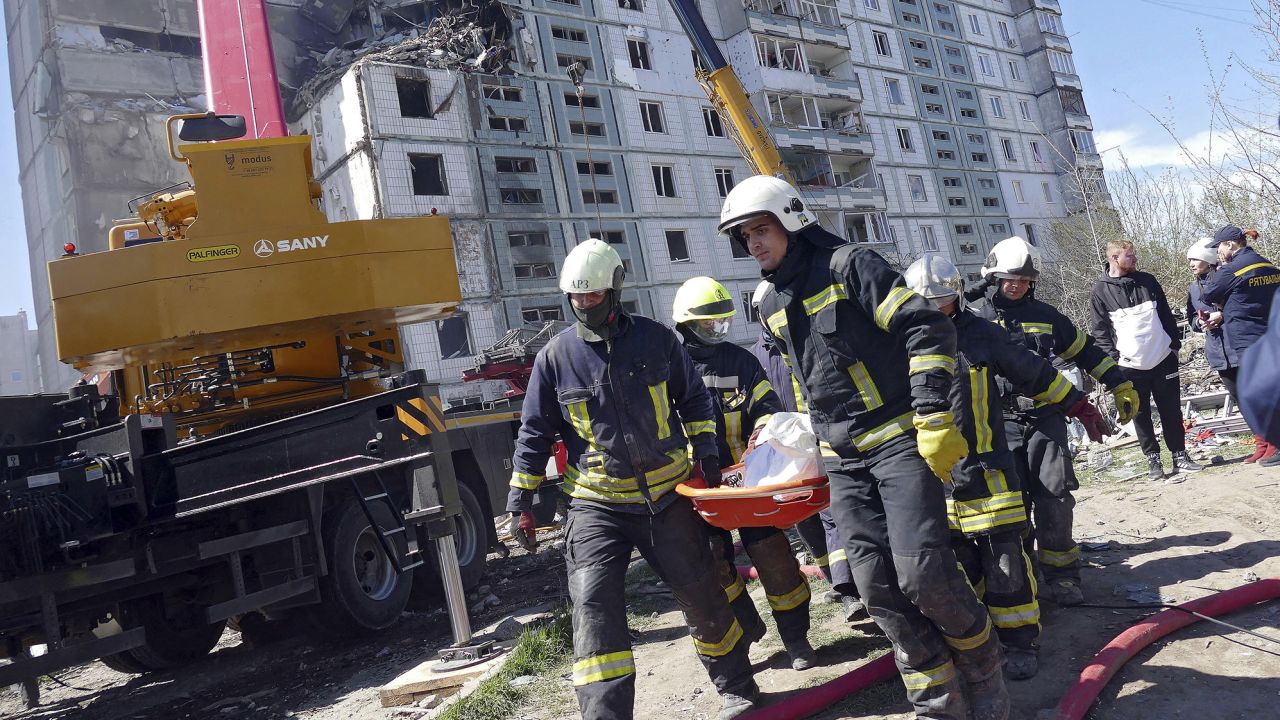 Rescuers carry the body of a victim found under the rubble at a block of flats destroyed in a Russian rocket attack on Uman, in central Ukraine's Cherkasy region, on April 28, 2023.