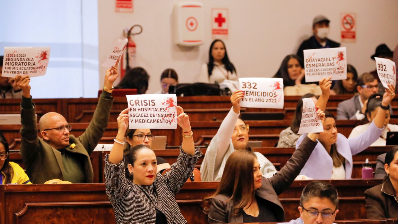 Opposition assembly members hold up signs in protest to the country's problems such as migration, health crisis, femicide and increased violence during a hearing in Quito on April 26.