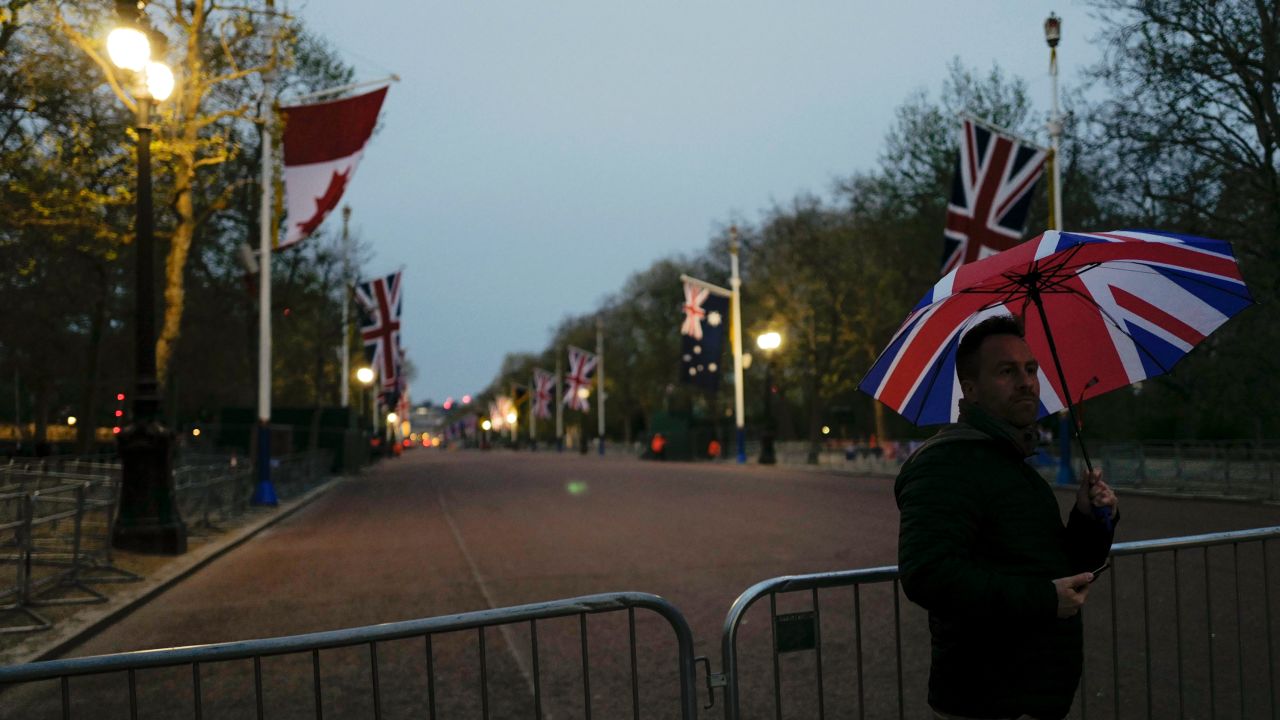 A man holds a Union-flag themed umbrella as he takes a picture on the Mall, ahead of the coronation of Britain's King Charles III.