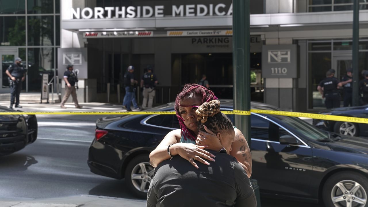 Angela Cooper and Jamese Nathan embrace outside of Northside Hospital medical facility as police officers work the scene of a shooting on May 3, 2023 in Atlanta, Georgia. 