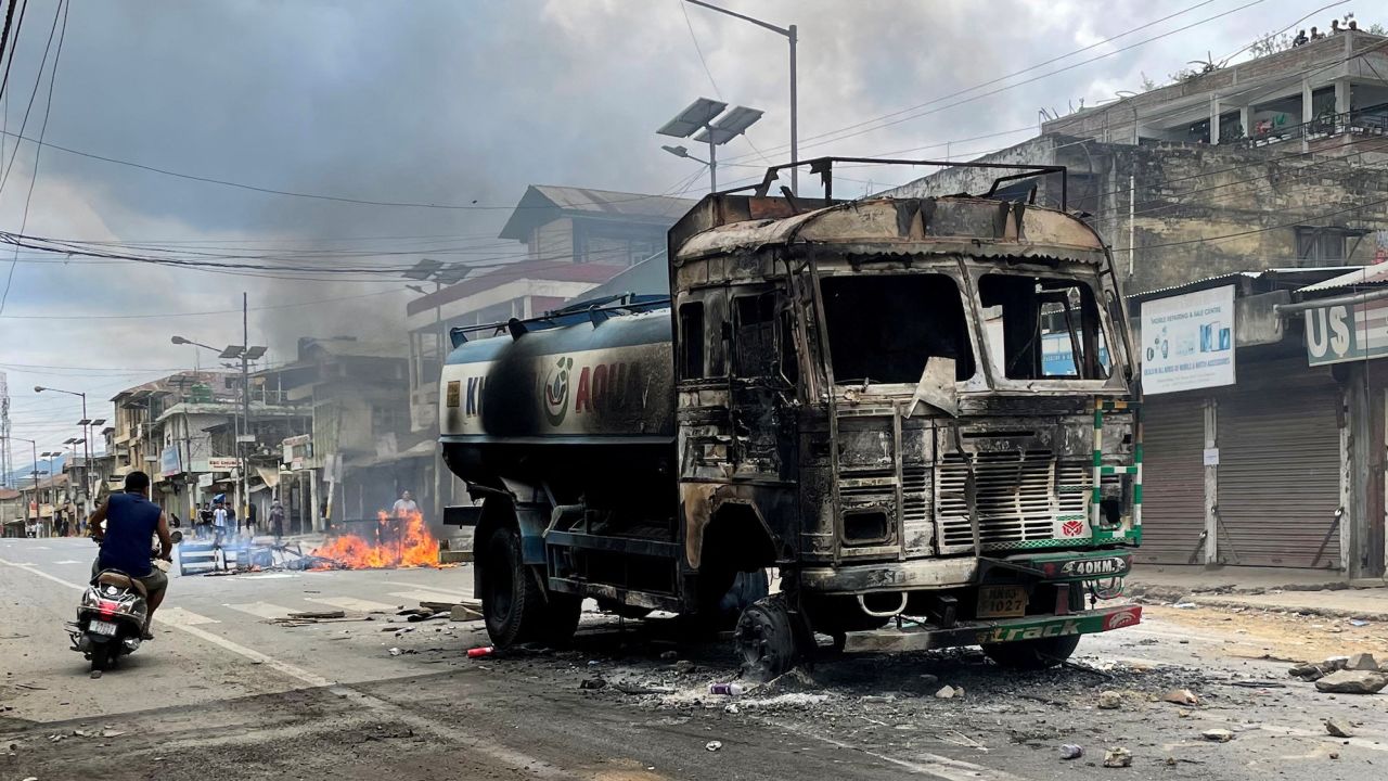 A scooterist rides past a damaged water tanker that was set afire during a protest by tribal and non-tribal groups in the northeastern state of Manipur, India, May 4, 2023.