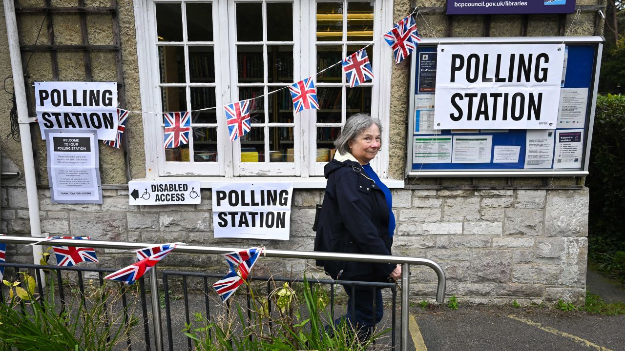 A woman leaves a polling station in Poole, southern England, as people vote in local elections.