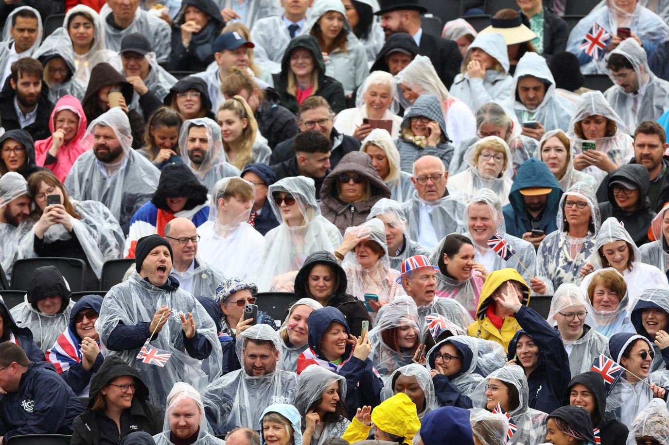 People gather to watch the procession. Showers moved through London on Friday and <a href='https://www.cnn.com/uk/live-news/king-charles-iii-coronation-ckc-intl-gbr/h_0cf74794c8e0be8ca222db150c2ccb94' target='_blank'>more rain was expected for Saturday</a>.