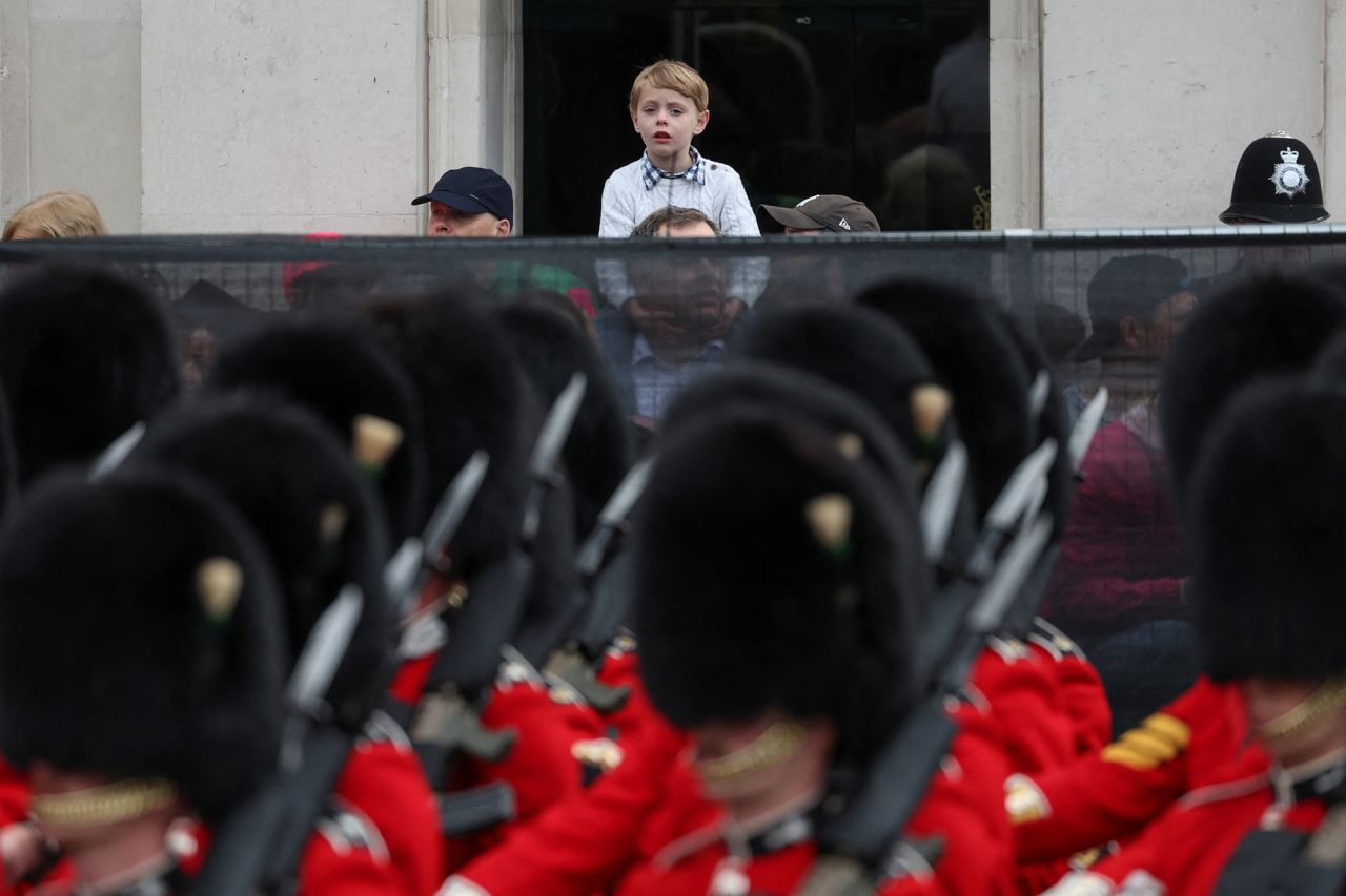 A boy watches guards march on the streets in front of Big Ben.