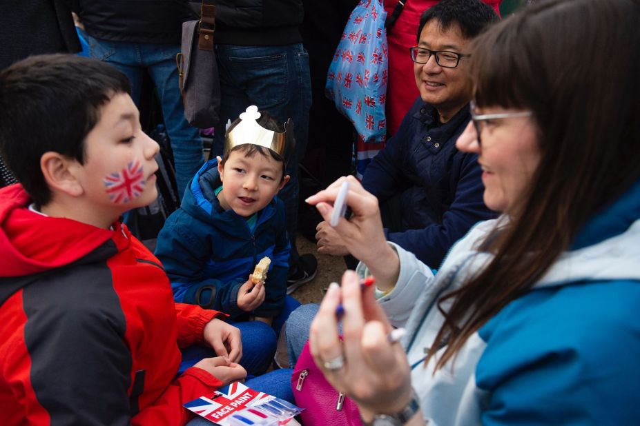 A child has paint applied to his face while waiting for the procession.