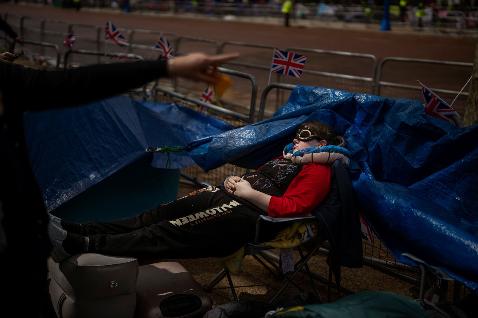 A royal fan sleeps along the procession route on Friday.