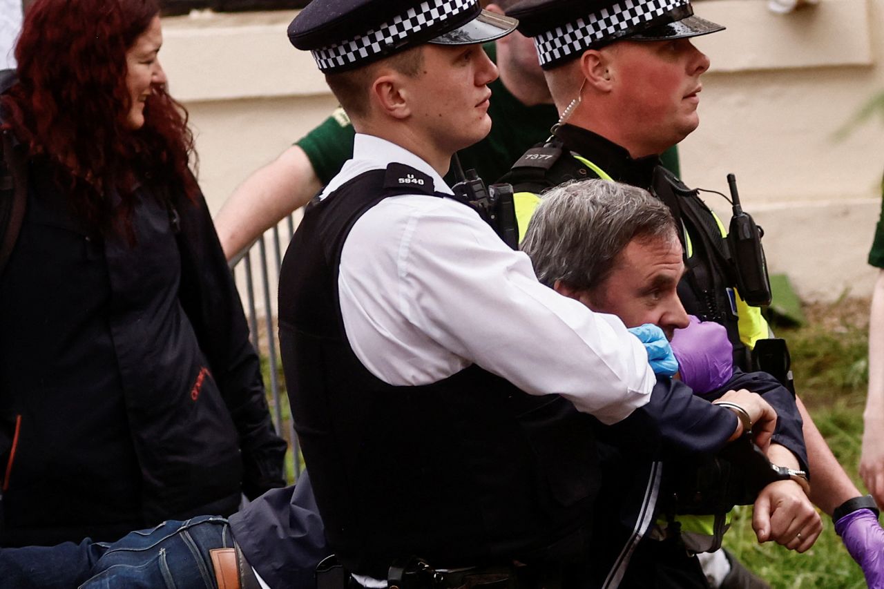 Police officers detain a protester ahead of the King's procession. <a href="https://www.cnn.com/uk/live-news/king-charles-iii-coronation-ckc-intl-gbr/h_089ce3083553388e9051d6c7fd26c7b0" target="_blank">Several arrests were made Saturday</a> as protesters gathered near the procession route.