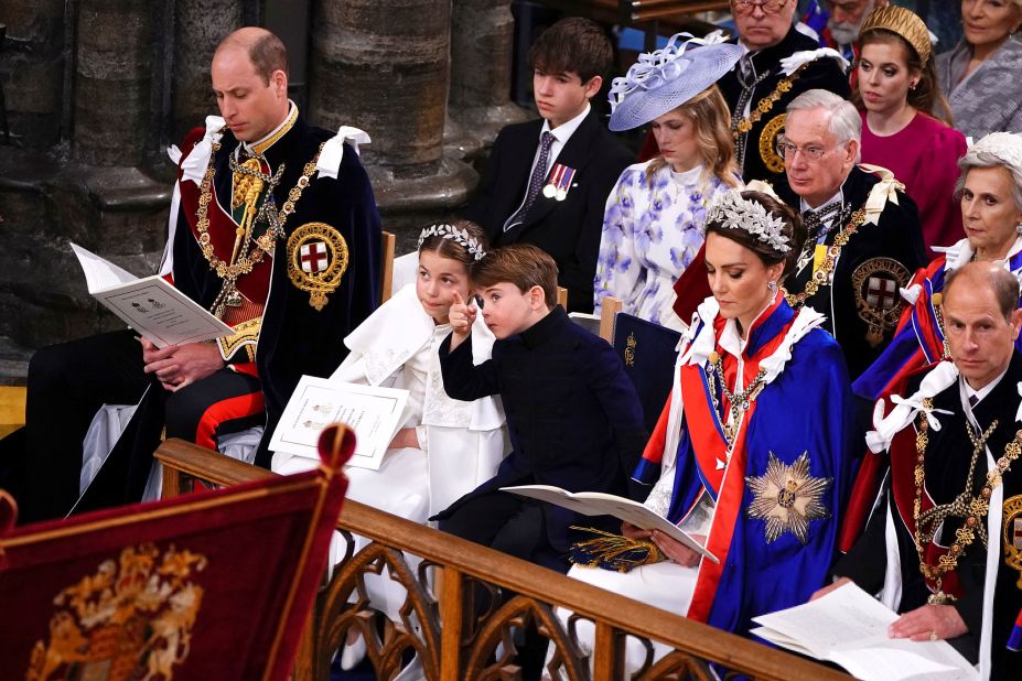 Prince Louis points out something to his sister, Princess Charlotte, during the ceremony. They are flanked by their parents, Prince William and Catherine, the Princess of Wales.