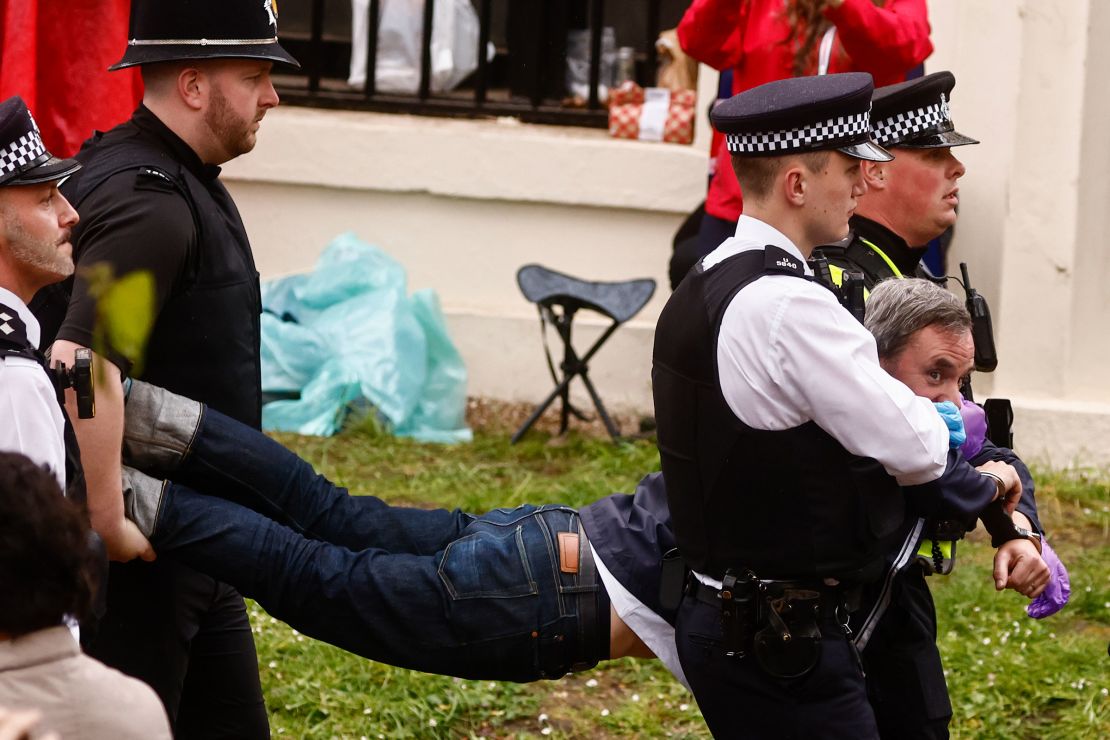 Police officers detain a protester as people gather to watch the procession during the coronation on Saturday.