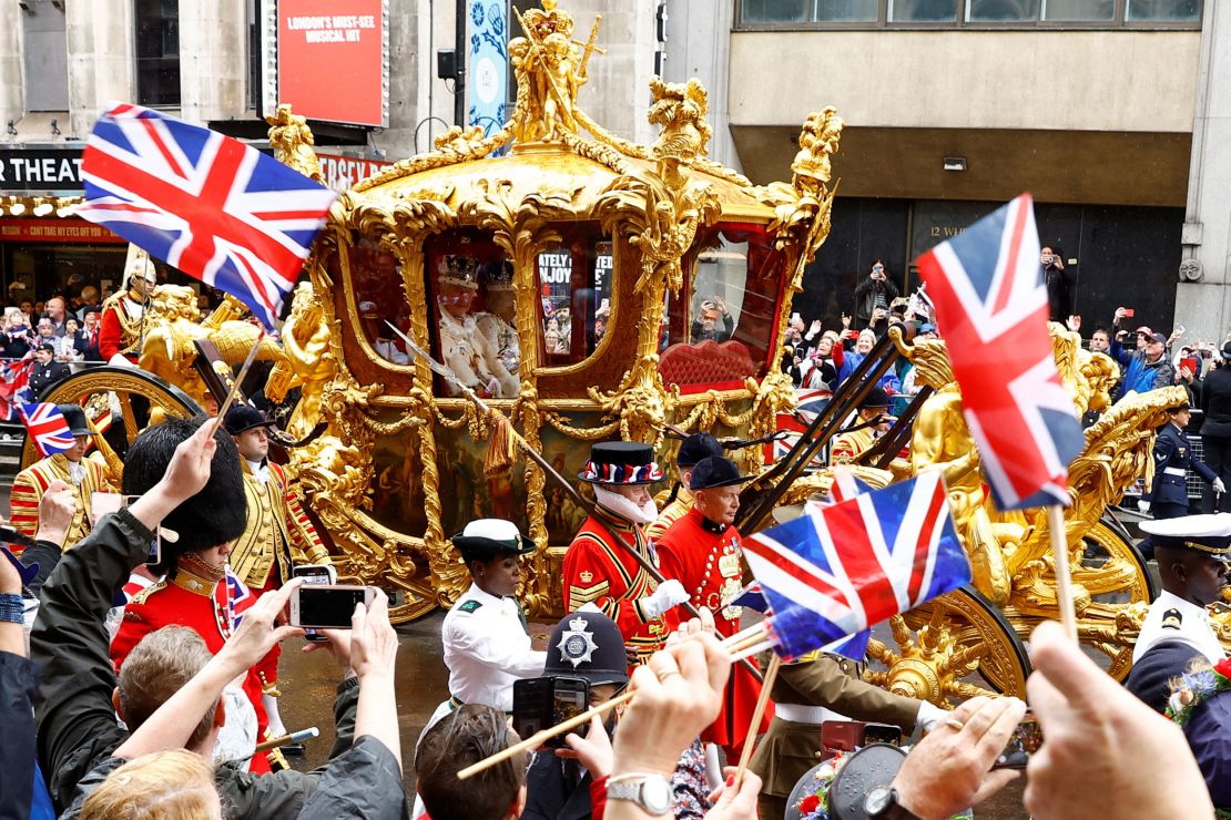 People wave flags as Britain's King Charles and Queen Camilla travel from Westminster Abbey in the Gold State Coach, following their coronation ceremony, in London, Britain May 6, 2023. REUTERS/John Sibley