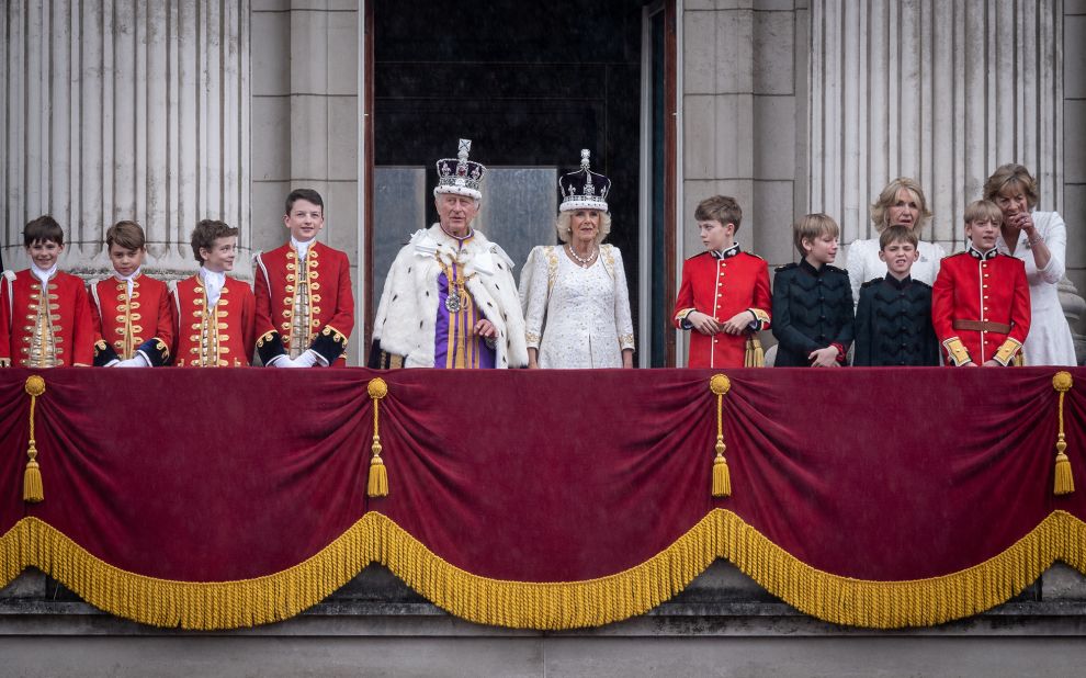 The King and Queen stand on the balcony of Buckingham Palace after the coronation. They are joined here by pages of honor who attended them throughout the day. One of the pages was the King's eldest grandson, Prince George, who can be seen second from left.