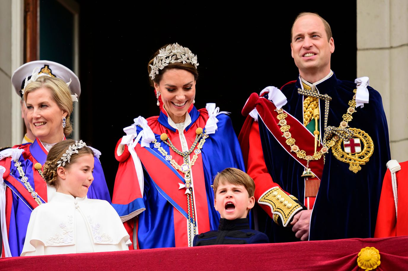 Prince Louis is looked at by his sister, Princess Charlotte, and his mother, Catherine, on the balcony of Buckingham Palace. At right is his dad, Prince William. On the far left is Sophie, the Duchess of Edinburgh.