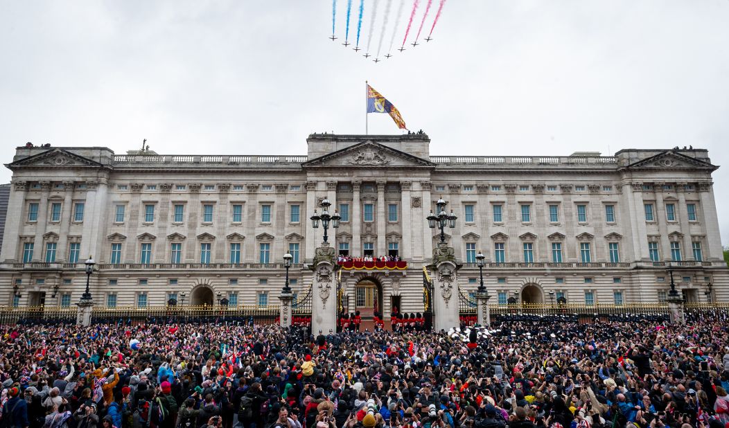 The crowd outside Buckingham Palace watches the Red Arrows fly by as the royals stand on the balcony.