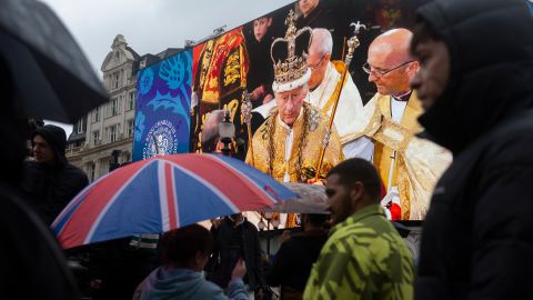 People pass in front of a screen showing an image from King Charles III coronation in Piccadilly Circus, London, following the event on May 6