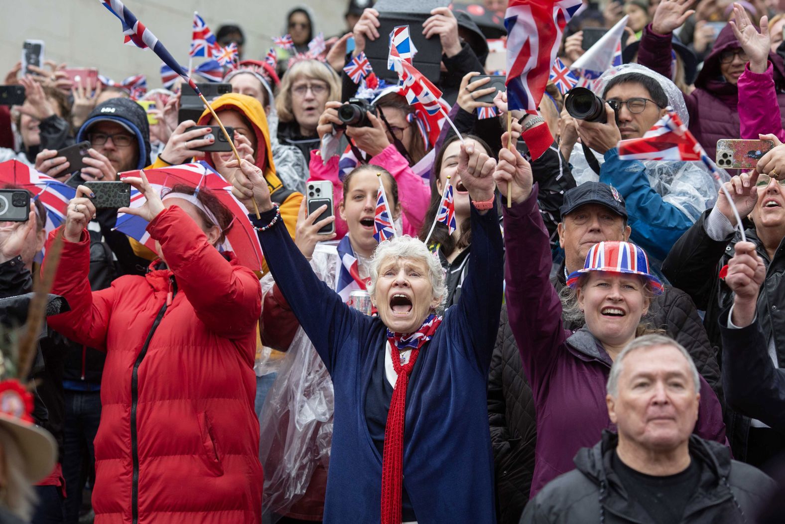 Members of the public watch the coronation procession on Saturday along the Mall in central London.