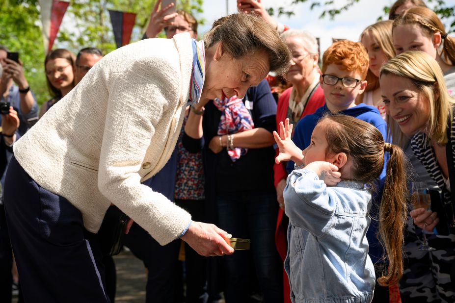 Princess Anne, the King's sister, presents a young girl with a commemorative tin of old coins during celebrations in Swindon, England.