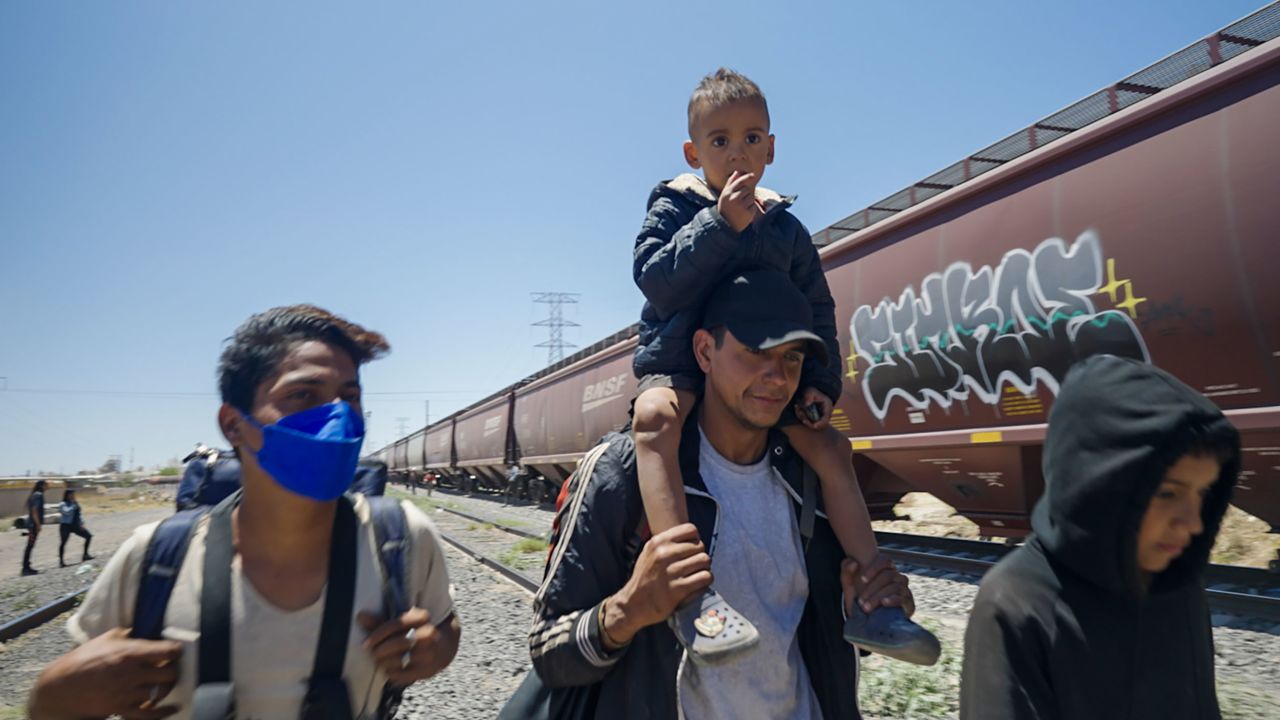 Leuman Varela, center, carries his son Luca after four and a half days riding on top of a freight train on May 7, 2023.