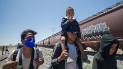 Leuman Varela, center, carries his son Luca after four and a half days riding on top of a freight train on May 7, 2023.